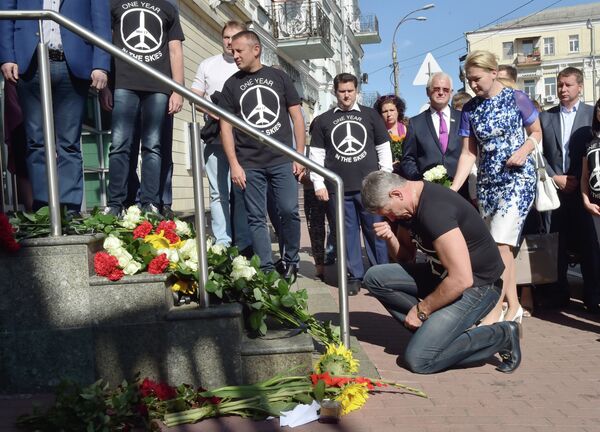 A man kneels down in front of flowers laid in front of the Dutch embassy in Kiev on July 17, 2015 in memory of the people who died in the crash of Malaysian Airlines flight MH17 - Sputnik International