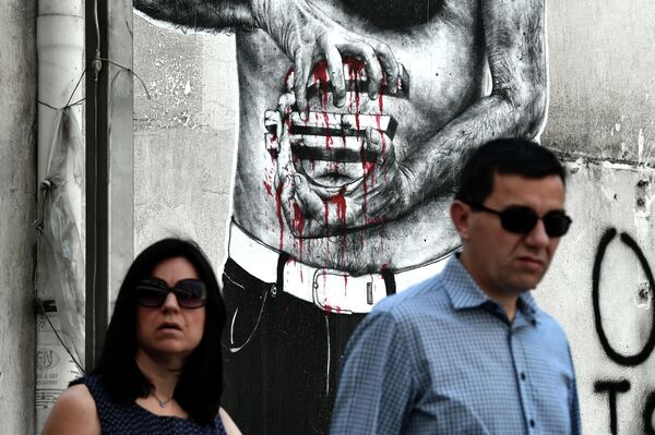 People pass by a graffiti showing a euro sign bleeding, in central Athens on July 14, 2015 People pass by a graffiti showing a euro sign bleeding, in central Athens on July 14, 2015 - Sputnik International
