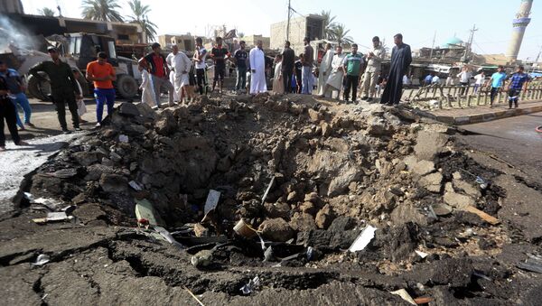 Iraqi men look at a crater left by a massive suicide car bomb attack carried out the previous day by the Islamic State group in the predominantly Shiite town of Khan Bani Saad, 20 km north of Baghdad, on July 18, 2015 - Sputnik International