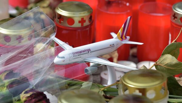 A model of a plane is placed between candles and flowers in front of the Germanwings headquarters in Cologne, western Germany for the victims of the plane crash two weeks ago in the French Alps, Tuesday, April 7, 2015 - Sputnik International
