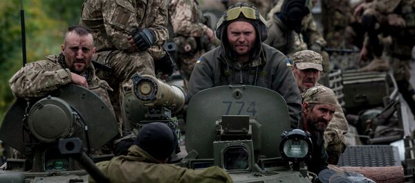 In this photo taken Tuesday, July 14, 2015, Ukrainian servicemen ride atop an armored vehicle near Krasnoarmiisk, Donetsk region, eastern Ukraine - Sputnik International