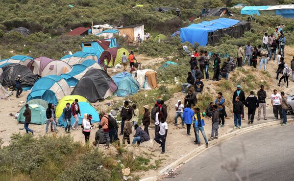 Migrants stand next to tents in the New Jungle in Calais on June 17, 2015 near the ferry port of Calais, northern France - Sputnik International