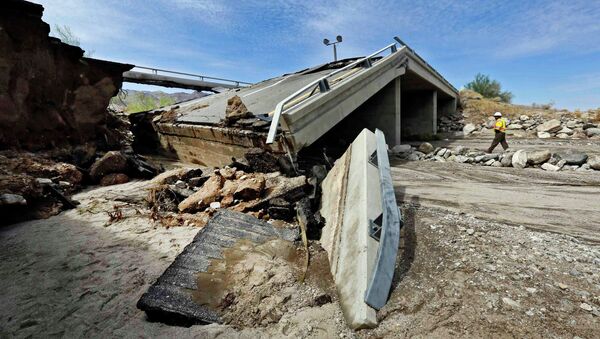 A worker walks near a washed-out bridge near the town of Desert Center, along Interstate 10 in Southern California, on Monday, July 20, 2015. All traffic along one of the major highways connecting California and Arizona was blocked indefinitely when the bridge over a desert wash collapsed during a major storm, and the roadway in the opposite direction sustained severe damage. - Sputnik International