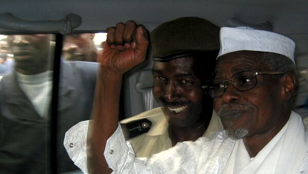Former Chad President Hissene Habre (R) raises his fist in the air as he leaves a court in Dakar escorted by a Senegalese policeman in this November 25, 2005 file photo - Sputnik International