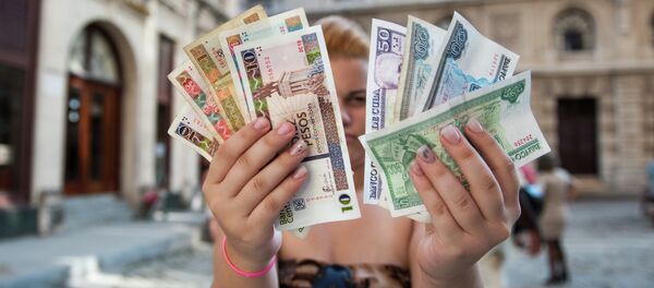 A Cuban shows Cuban Pesos CUP (Left hand) and Convertible Pesos CUC (Right hand) A Cuban shows Cuban Pesos CUP (Left hand) and Convertible Pesos CUC (Right hand) - Sputnik International