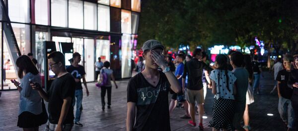 In this picture taken on July 15, 2015, people gather in front of a Uniqlo clothes store in Beijing. In this picture taken on July 15, 2015, people gather in front of a Uniqlo clothes store in Beijing. - Sputnik International