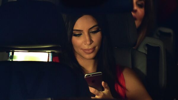 US reality TV star Kim Kardashian looks at her iPhone as she sits in a car after visiting the genocide memorial, which commemorates the 1915 mass killing of Armenians in the Ottoman Empire, in Yerevan on April 10, 2015 - Sputnik International