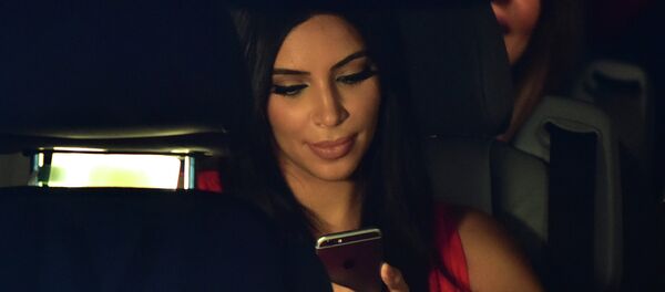 US reality TV star Kim Kardashian looks at her iPhone as she sits in a car - Sputnik International