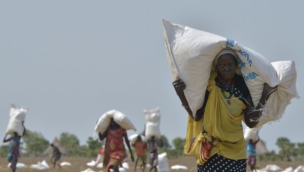 A woman carries a sack of food aid after a food-drop in a field on February 23, 2015 at a village in Nyal, Panyijar county, near the northern border with Sudan - Sputnik International
