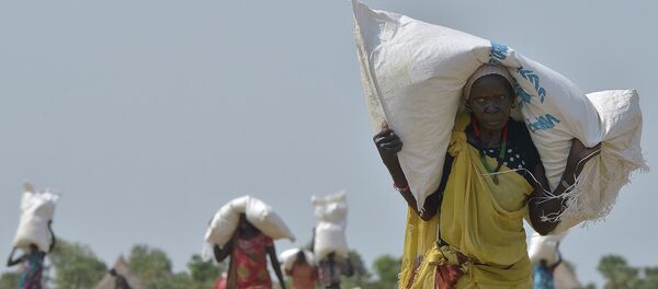 A woman carries a sack of food aid after a food-drop in a field on February 23, 2015 at a village in Nyal, Panyijar county, near the northern border with Sudan - Sputnik International