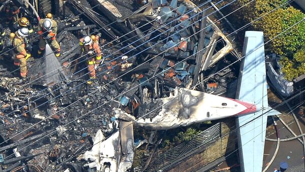 An aerial view shows debris of a crashed light plane and burning house are seen after the plane went down in a residential area and burst into flames, in Chofu, outskirt of Tokyo, in this photo taken by Kyodo July 26, 2015. - Sputnik International