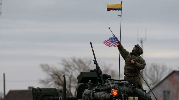A member of US Army’s 2nd Cavalry Regiment raises the US flag on a Stryker vehicle during the ''Dragoon Ride'' military exercise, in Salociai some 178 kms (110 miles) north of the capital Vilnius, Lithuania, Monday, March 23, 2015 - Sputnik International