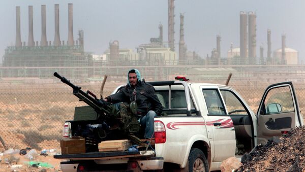 In this March 5, 2011 file photo, an anti-government rebel sits with an anti-aircraft weapon in front an oil refinery, after the capture of the oil town of Ras Lanouf, eastern Libya. - Sputnik International