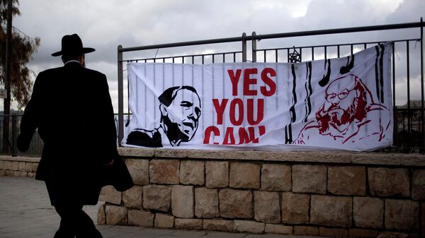 An ultra-Orthodox Jewish man walks past a banner depicting U.S. President Barack Obama, and Jonathan Pollard, a Jewish-American who was jailed for life in 1987 on charges of spying on the United States. - Sputnik International
