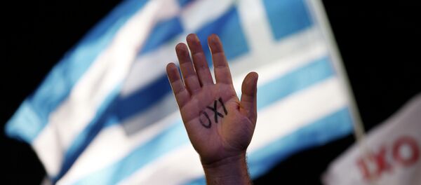 A demonstrator raises his hand with the Greek word ''No'' written on it in front of a Greek flag during a rally in support of the no vote to an upcoming referendum called by Premier Alexis Tsipras on whether to accept the terms of an international bailout, in Athens, in this photo dated Friday, July 3, 2015. A demonstrator raises his hand with the Greek word ''No'' written on it in front of a Greek flag during a rally in support of the no vote to an upcoming referendum called by Premier Alexis Tsipras on whether to accept the terms of an international bailout, in Athens, in this photo dated Friday, July 3, 2015. - Sputnik International
