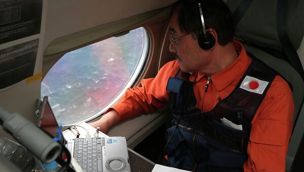 Communications specialist Hidetaka Sato on a Japan Coast Guard Gulfstream aircraft, looks out of a window searching for the missing Malaysia Airlines Flight MH370 in Southern Indian Ocean, near Australia, Tuesday, April 1, 2014. - Sputnik International