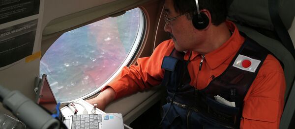 Communications specialist Hidetaka Sato on a Japan Coast Guard Gulfstream aircraft, looks out of a window searching for the missing Malaysia Airlines Flight MH370 in Southern Indian Ocean, near Australia, Tuesday, April 1, 2014. - Sputnik International