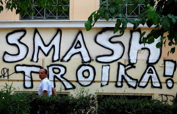 A pedestrian passes graffiti referring to the officials from the European Union, European Central Bank and International Monetary Fund, together known as the troika, in Athens, Wednesday, July 29, 2015. - Sputnik International