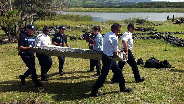 Police carry a piece of debris from an unidentified aircraft found in the coastal area of Saint-Andre de la Reunion, in the east of the French Indian Ocean island of La Reunion, on July 29, 2015 - Sputnik International