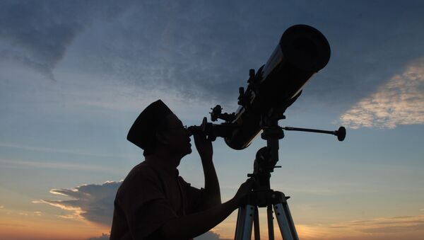 In this photograph taken on August 10, 2010 an official from the State Islamic University (STAIN), uses a telescope to observe the moon after sunset from the coast of Madura in East Java province of Indonesia on the eve of Ramadan - Sputnik International
