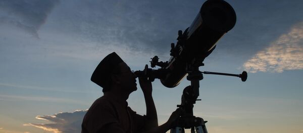 In this photograph taken on August 10, 2010 an official from the State Islamic University (STAIN), uses a telescope to observe the moon after sunset from the coast of Madura in East Java province of Indonesia on the eve of Ramadan - Sputnik International