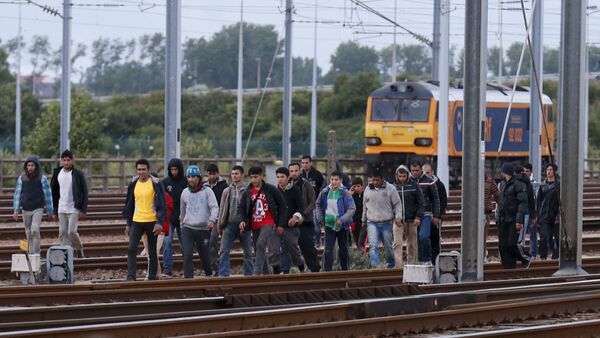 Migrants make their way along train tracks as they attempt to access the Channel Tunnel in Frethun, near Calais, France, July 29, 2015 - Sputnik International
