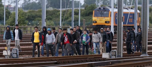 Migrants make their way along train tracks as they attempt to access the Channel Tunnel in Frethun, near Calais, France, July 29, 2015 - Sputnik International