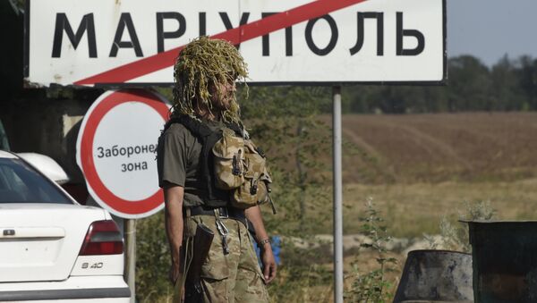 A Ukrainian army soldier walks past a city road sign reading Mariupol on September 4, 2014 - Sputnik International