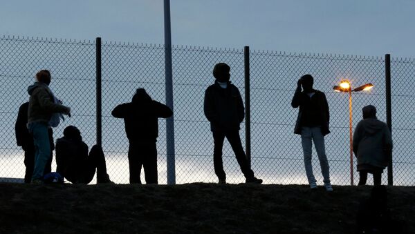 Migrants are seen in silhouette as they stand on a rise near a fence as they gather near the Channel Tunnel access in Frethun, near Calais, France, July 30, 2015 - Sputnik International