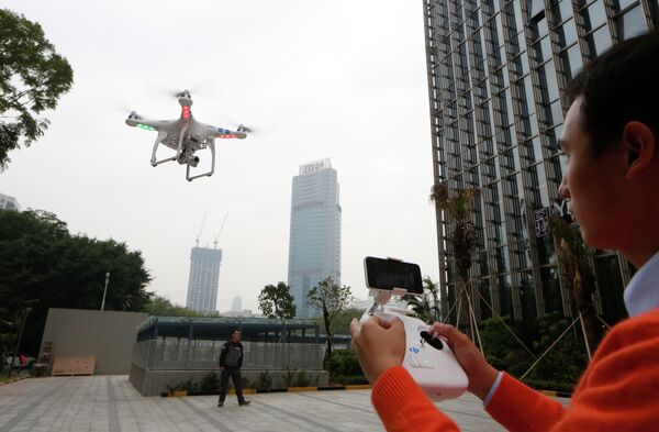 An employee from DJI Technology Co. demonstrates the remote flying with his Phantom 2 Vision+ drone in Shenzhen, south China's Guangdong province.  - Sputnik International