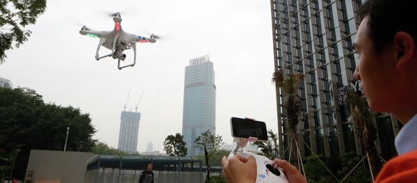 An employee from DJI Technology Co. demonstrates the remote flying with his Phantom 2 Vision+ drone in Shenzhen, south China's Guangdong province. - Sputnik International