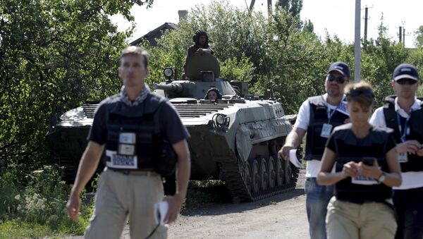 Members of the Organisation for Security and Co-operation in Europe (OSCE) walk past an armoured personnel carrier (APC) of the self-proclaimed Donetsk People's Republic forces outside the village of Novolaspa in Donetsk region, Ukraine, July 19, 2015 - Sputnik International
