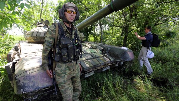 A member of the Organisation for Cooperation and Security in Europe (OSCE) Mission poses on a tank as he and others control the withdrawal of heavy weapons from independence supporters at the line of contact with Ukrainian forces, near Donetsk on July 19, 2015 - Sputnik International