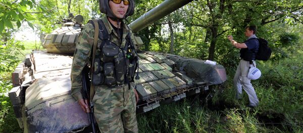 A member of the Organisation for Cooperation and Security in Europe (OSCE) Mission poses on a tank as he and others control the withdrawal of heavy weapons from independence supporters at the line of contact with Ukrainian forces, near Donetsk on July 19, 2015 A member of the Organisation for Cooperation and Security in Europe (OSCE) Mission poses on a tank as he and others control the withdrawal of heavy weapons from independence supporters at the line of contact with Ukrainian forces, near Donetsk on July 19, 2015 - Sputnik International