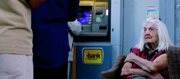A pensioner looks at customers who use an ATM as she sits outside a bank in Athens, Wednesday, July 1, 2015. - Sputnik International
