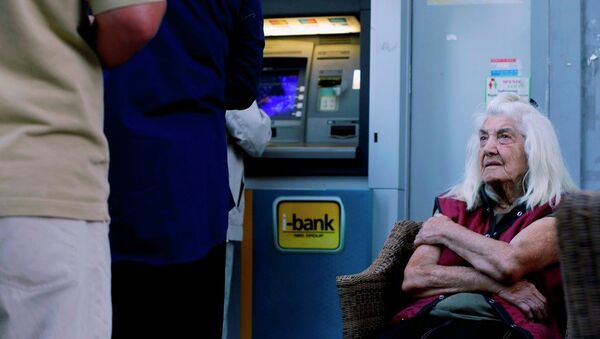 A pensioner looks at customers who use an ATM as she sits outside a bank in Athens, Wednesday, July 1, 2015. - Sputnik International