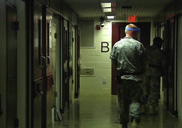 Soldiers walk past detainees' cells during early morning prayer at Guantanamo Bay Naval Base, Camp 5, in Cuba - Sputnik International