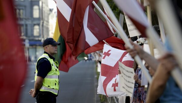 A police officer looks on as people attend a protest against European Union plans to host 250 refugees in Latvia over the next 2 years, in Riga, Latvia, August 4, 2015 - Sputnik International