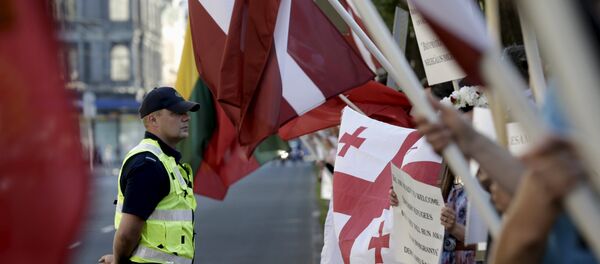 A police officer looks on as people attend a protest against European Union plans to host 250 refugees in Latvia over the next 2 years, in Riga, Latvia, August 4, 2015 - Sputnik International