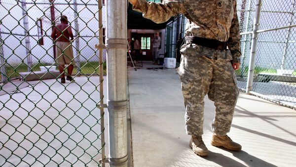 In this photo, reviewed by the US Military, a guard leans on a fencepost as a Guantanamo detainee, left, jogs inside the exercise yard at Camp 5 detention center, the U.S. Naval Base, in Guantanamo Bay, Cuba, January 21, 2009 - Sputnik International
