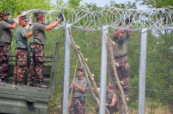 A picture is taken on July 18, 2015 shows soldiers of the Hungarian Army's technical unit finish the first completed elements of the 150 meter-long metal fence at the Hungarian-Serbian border nearby Morahalom village. A picture is taken on July 18, 2015 shows soldiers of the Hungarian Army's technical unit finish the first completed elements of the 150 meter-long metal fence at the Hungarian-Serbian border nearby Morahalom village. - Sputnik International