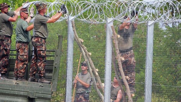 A picture is taken on July 18, 2015 shows soldiers of the Hungarian Army's technical unit finish the first completed elements of the 150 meter-long metal fence at the Hungarian-Serbian border nearby Morahalom village. - Sputnik International