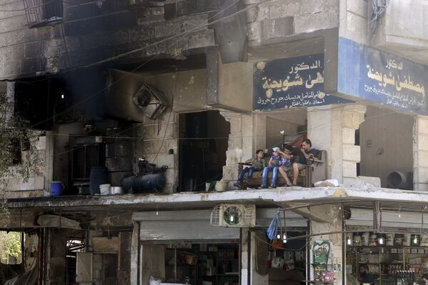 Residents sit on a couch on a balcony of a damaged building in Aleppo's al-Shaar neighboirhood, Syria, August 1, 2015. - Sputnik International