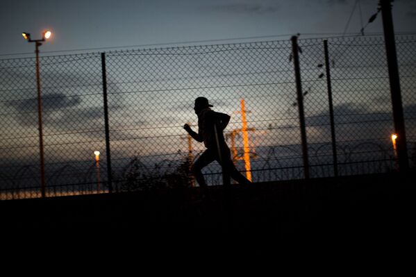 A migrant runs after crossing a fence as he attempts to access the Channel Tunnel, in Calais, northern France, Monday, Aug. 3, 2015. - Sputnik International