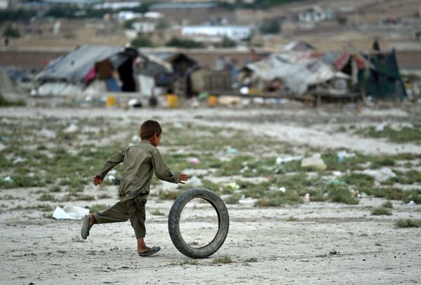 An Afghan Kochi nomad boy plays with a tire outside his tent on the outskirts of Kabul on August 2, 2015 - Sputnik International