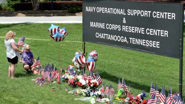 Two women place American flags by a makeshift memorial at the entrance to the Naval Operational Support Center and Marine Reserve Center in Chattanooga, Tennessee. - Sputnik International