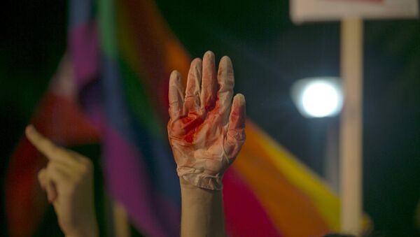 A protester holds up a glove covered in red during a protest against the violence towards the gay community in Tel Avi - Sputnik International