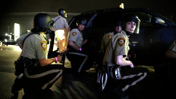 Police take cover behind a vehicle during a protest in Ferguson, Mo., Sunday, Aug. 9, 2015 - Sputnik International