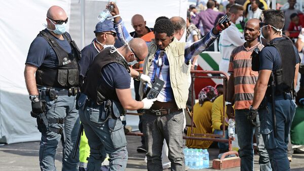 A police officer uses and hand held metal detector to check a man as he disembark from the patrol vessel Fiorillo of the Italian Coast Guard after it arrived in the port of Pozzallo on August 7, 2015 after saving some 387 migrants in the Sicilian Channel - Sputnik International