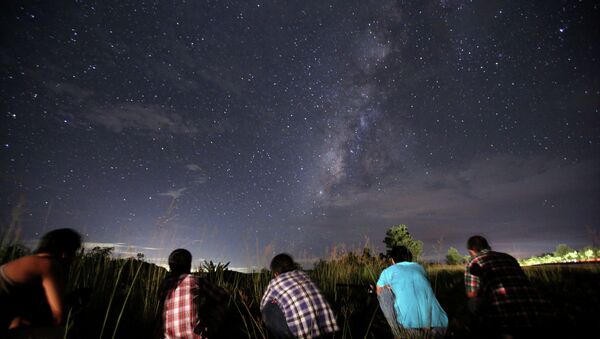 This long-exposure photograph taken on August 12, 2013 shows people watching for the Perseid meteor shower in the night sky - Sputnik International